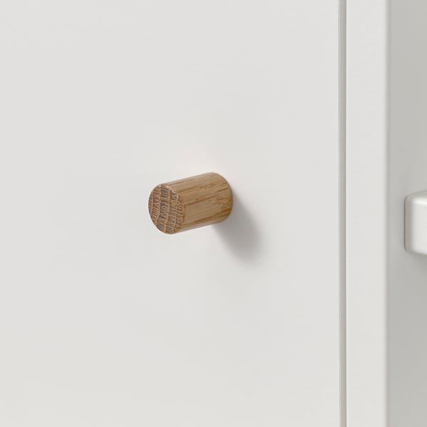 Liten krok i trä monterad på vit vägg. Enkel, naturlig och minimalistisk design. Perfekt för upphängning av handdukar eller tillbehör.