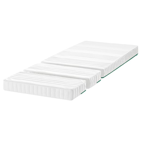 Tre vita madrasser staplade, rektangulära med gröna kanter, designade för att växa med ett barn.