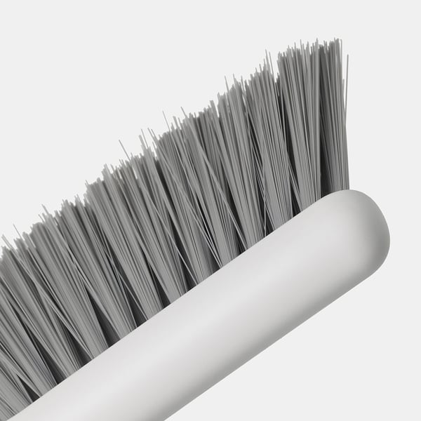 Närbild av en borste med täta, grå borst fästa på ett slätt, vitt cylindriskt handtag, som visar dess kvalitet och design.