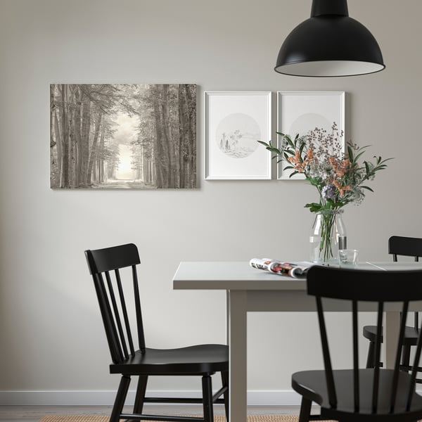Modern matplats med svarta stolar, bord och taklampa. Väggen har PJÄTTERYD bild, blommor och tidning.