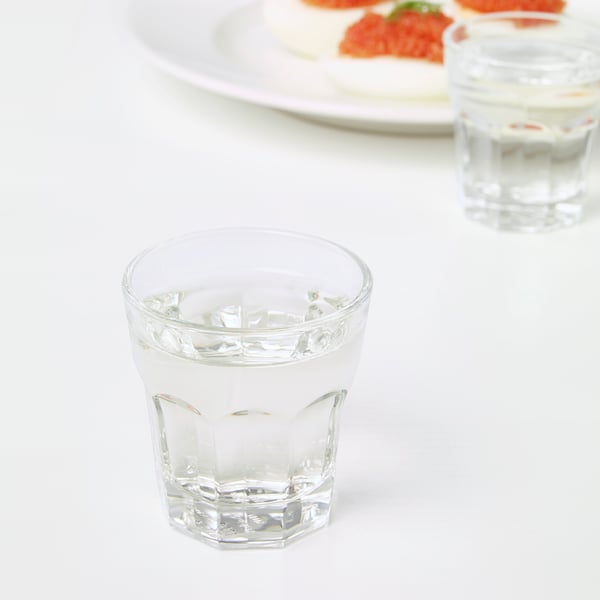 Två glas med is står på ett vitt bord, bredvid en tallrik med mat.