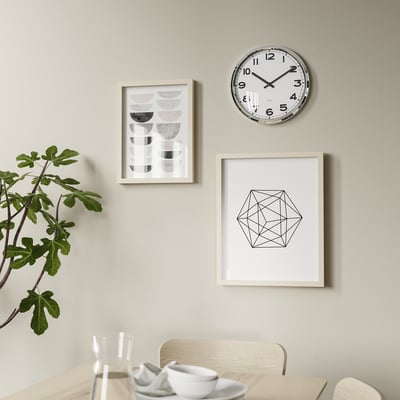 Modern matsal med rund klocka, konst och växter.