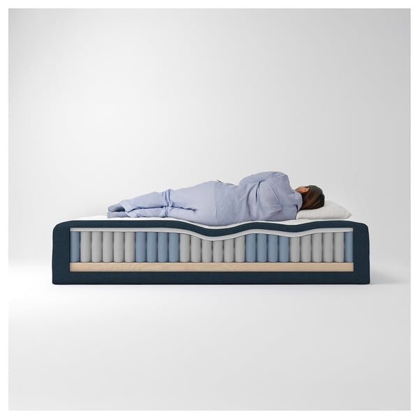 En person som sover på en madrass med flera lager, inklusive massiv furu, polyester, polyuretanskum, stålfjädrar och återvunna material.