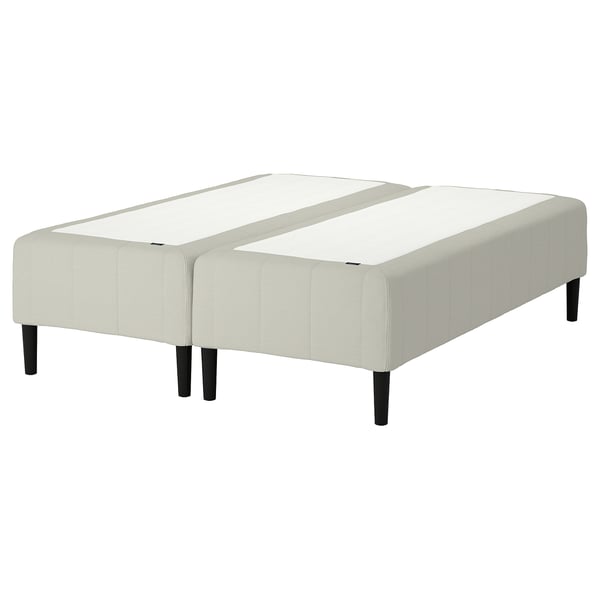 En RÅHOLMAR sängbotten, med en beige, vadderad design med träben och en delad madrasslayout för komfort och stöd.