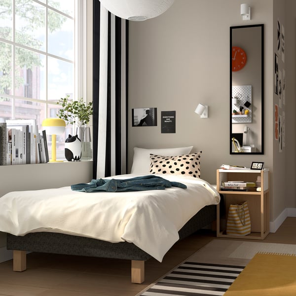 Modern sovrum med RANDÅSEN-vit säng, träsängbord, svartvit inredning, fönster med gardiner och randig matta.