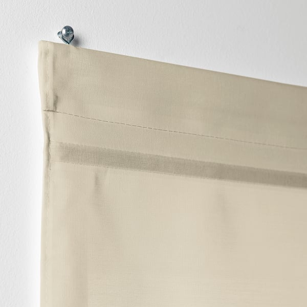 En beige RINGBLOMMA hissgardin är delvis upphöjd, vilket visar dess magnetiska höjningsfunktion och liner för ljusfiltrering.
