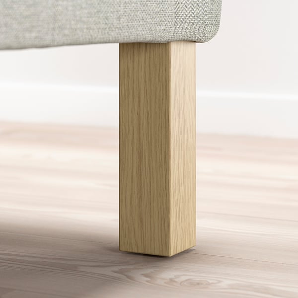 En närbild på en sängs träben och tygklädd bas.