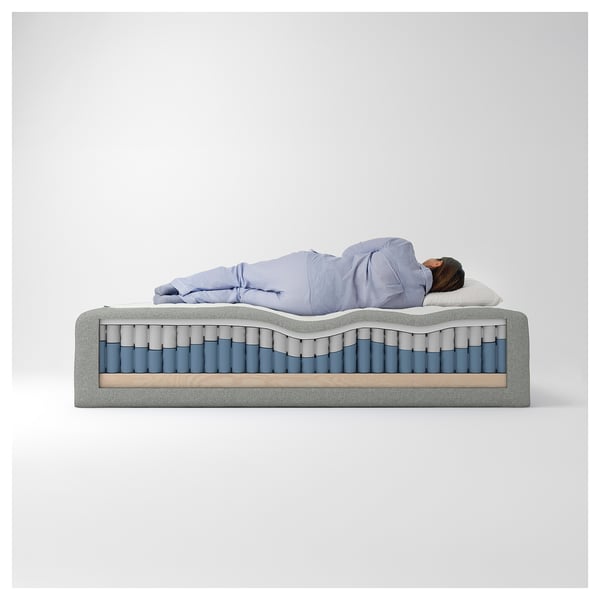 En person som sover på RISHÖJDEN-säng med pocketfjädrar, furubas, återvunnen polyester, polyuretanskum.