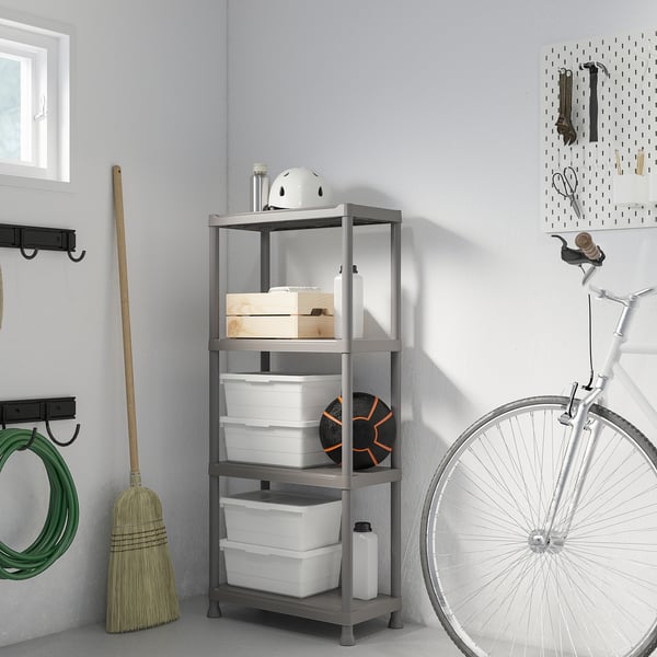 Grå RUNMARÖ plasthylla med förvaringsfack och sportutrustning, bredvid cykel och kvast.