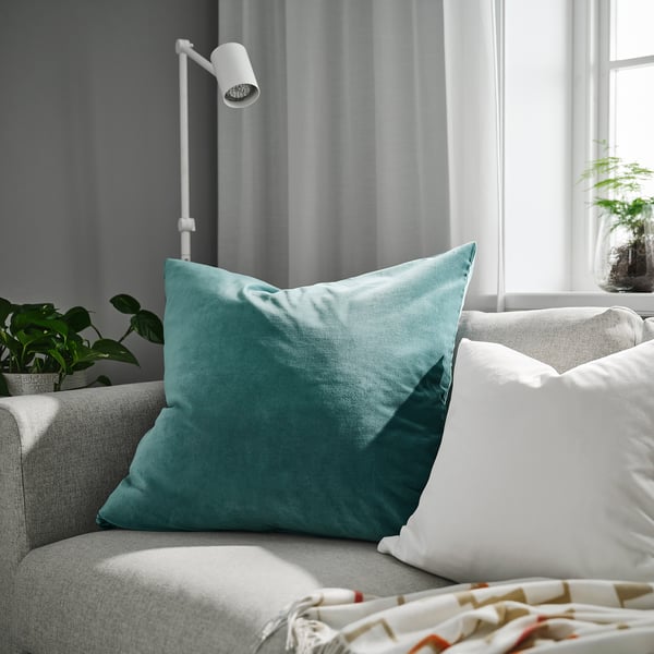 Kricka SANELA kudde på grå soffa. Mjuk sammet, perfekt för läsning i sängen, omgiven av inredning.