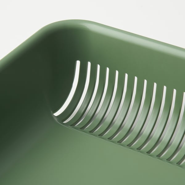Grön plastsil med flera slitsar för dränering av matavfall, avsedd för köksbruk.
