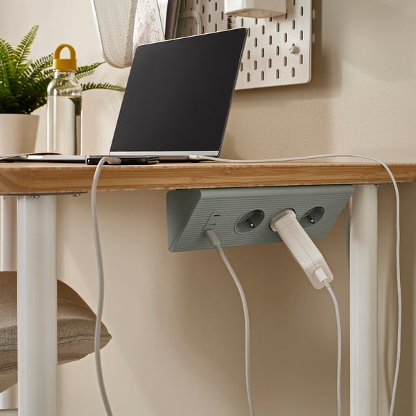 Minimalistisk skrivbordsuppsättning med bärbar dator och SKOTA-sladd, snyggt organiserad.
