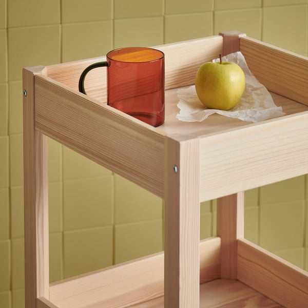 SKUGGSTUBB mugg & äpple på ljus träbricka. Bärnstensfärgad mugg kontrasterar grön vägg.