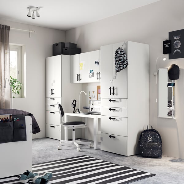 Modernt tonårsrum med vit SMÅSTAD förvaring, skrivbord, randig matta och svarta accessoarer.