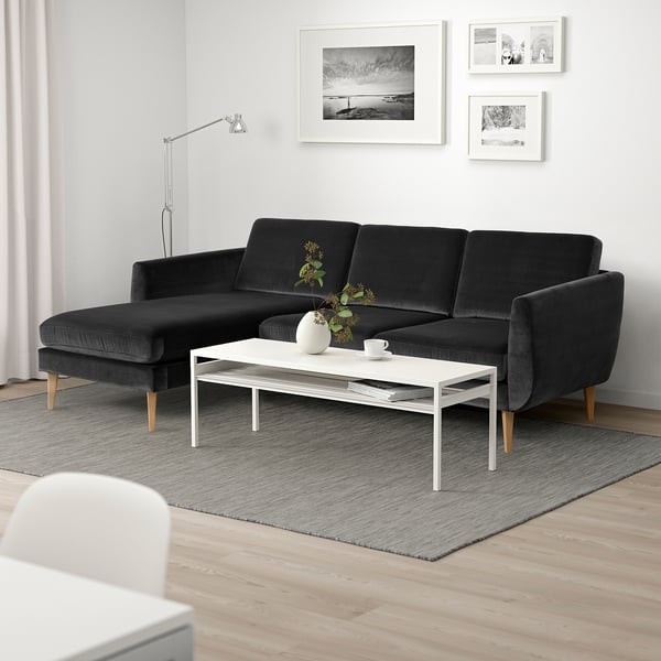 Modernt vardagsrum med sektionssoffa i retrostil, soffbord, väggkonst, lampa och matta - mysig minimalism.