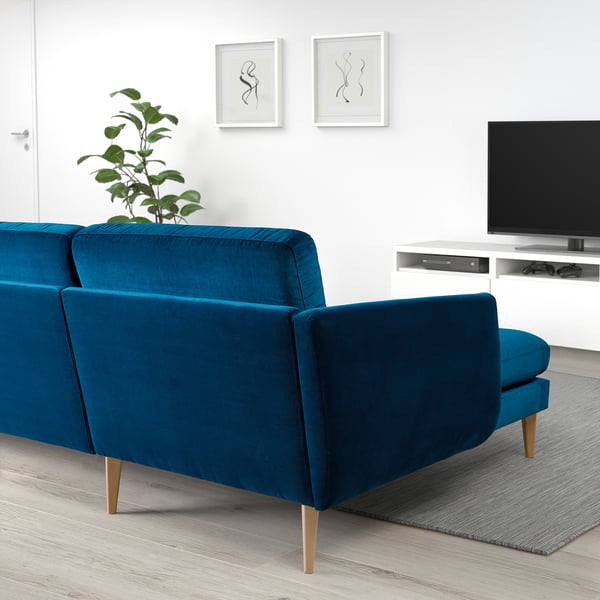 Modernt vardagsrum med stor blå SMEDSTORP soffa, träben, kuddar, tv-bänk och väggkonst. Soffan matchar rummens minimalistiska design.