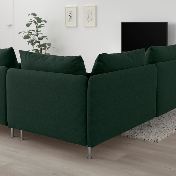 Mörkgrön sektionssoffa SÖDERHAMN med djupa sittplatser, mot vita väggar, bredvid en växt och tv, på ett ljust trägolv.