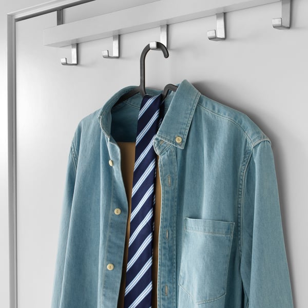 Klädhängare som rymmer blå skjorta med slips, på vit bakgrund.