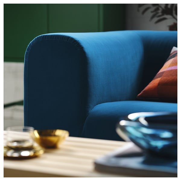 En livlig blå soffa med plyschkuddar som visar upp högkvalitativ design och komfort, placerad nära ett träbord med dekorativa föremål.