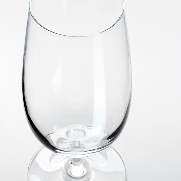 Ett klart, elegant vinglas med en slät stam som reflekterar ljus, mot en vit bakgrund.
