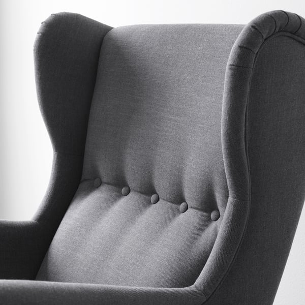 Elegant wingback-stol i närbild som visar upp tyg av hög kvalitet. Detaljerade sömmar och robust konstruktion.