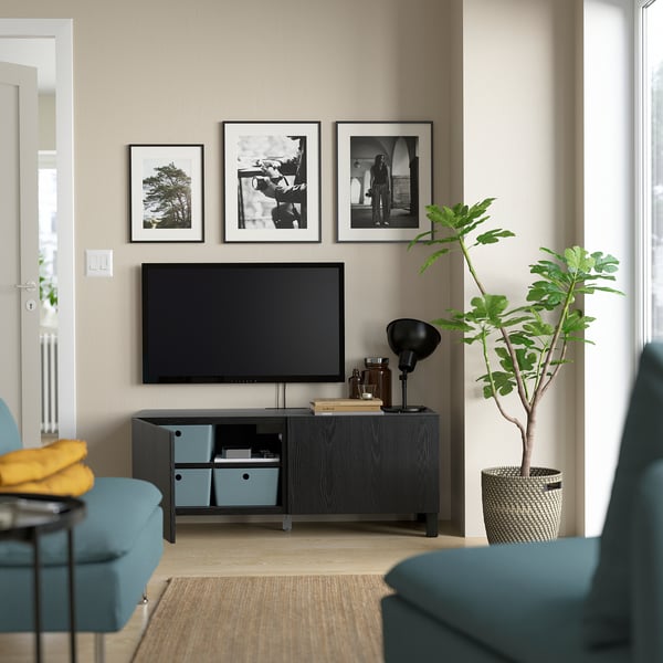 Modernt vardagsrum med plattskärms-tv, blå soptunnor, lampa, växt och svartvita foton
