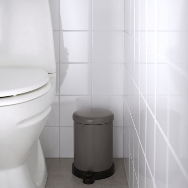 Grå TOFTAN-behållare med mjukstängande lock, bredvid toaletten, lätt att flytta och rengöra.