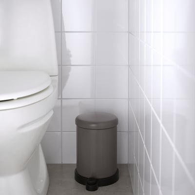 Grå TOFTAN-behållare med mjukstängande lock, bredvid toaletten, lätt att flytta och rengöra.
