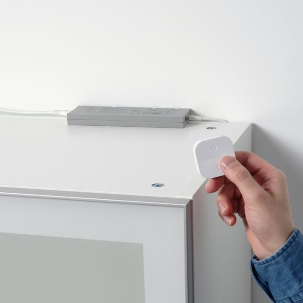Tryck för hand på den vita fjärrkontrollen nära fästet och styr smart belysning.