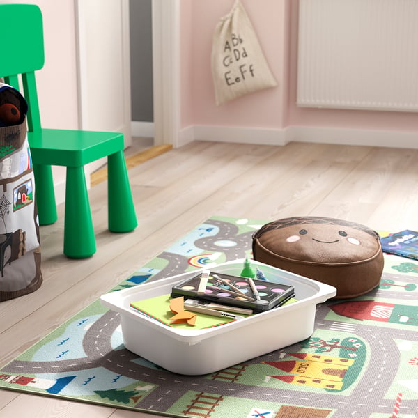 Lekplats för barn med TROFAST-förvaring, grön stol, leksaker och spelmatta. Träram, plastlådor med konstnärsmaterial, organiserat lekutrymme.