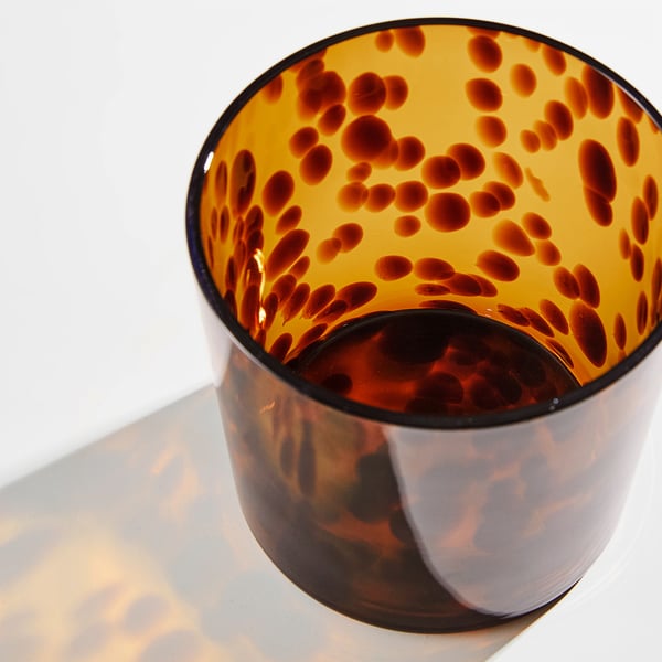 Vas i glas med svart insida spräcklig orange, mjukt upplyst.