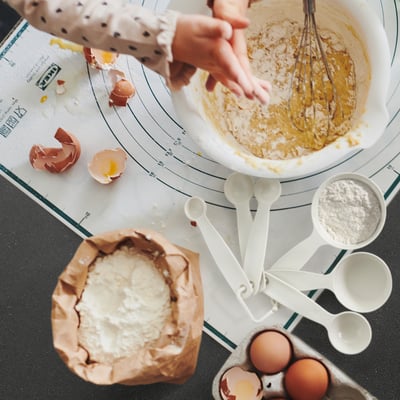 Exempel på bildbakningsscen: vit blandningsskål, äggskal, måttskedar, ägg, mjölpåse, UPPFYLLDA vita plastmåttkoppar.