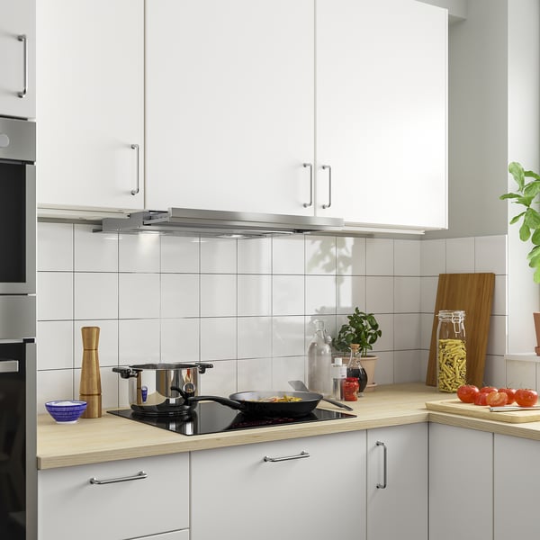 Modernt kök med vit UTDRAG-fläkt över bänkskiva i trä, köksredskap och växter.