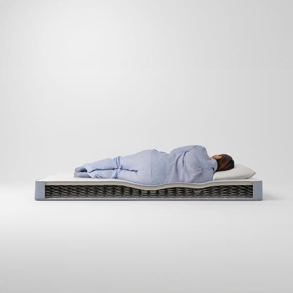 Person som sover på medelhög, blå VESTMARKA-madrass med skumlager och huvfjädrar.