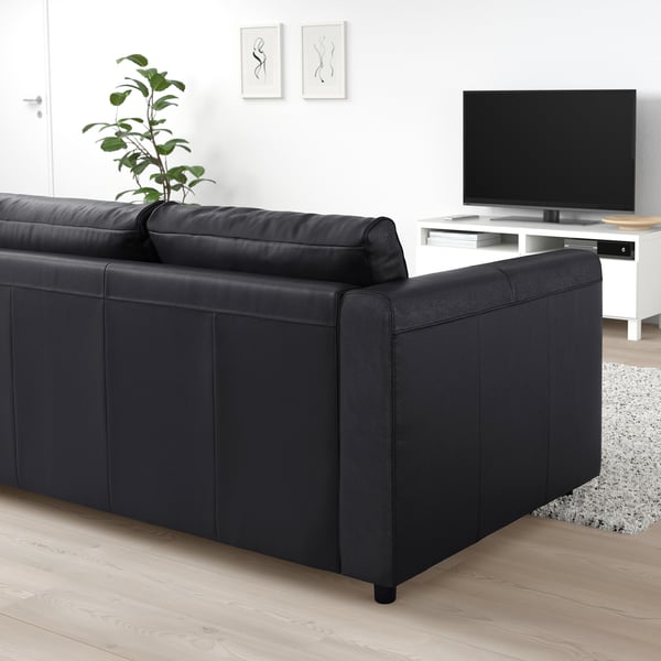 Modernt vardagsrum med VIMLE svart lädersoffa, plattskärms-tv och växt.