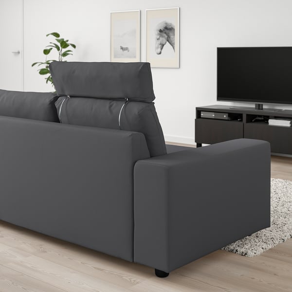 Modern grå VIMLE soffa i minimalistiskt vardagsrum. Stor, bekväm, med nackstöd och breda armstöd. Stor tv och växt i närheten.