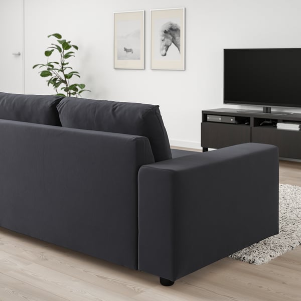 Modern mörkgrå VIMLE soffa med schäslong, stor plattskärms-tv och väggkonst.