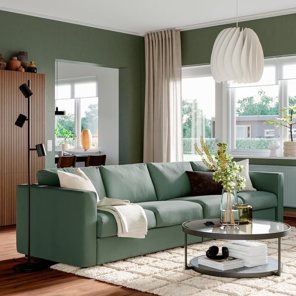 VIMLE grön soffa på matta med soffbord, böcker, vas. Träenhet, stort fönster, neutral inredning.