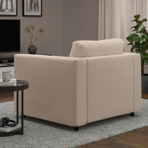 En beige VIMLE-fåtölj i ett vardagsrum som visar upp sitt mjuka, bekväma tyg och robusta design med trägolv och en matta under.