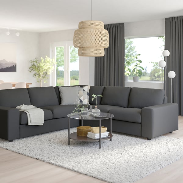 Modernt vardagsrum med VIMLE sektion, glasbord, matta och lampa. Stora fönster med gardiner.