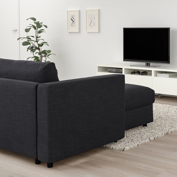 Modernt vardagsrum med grå VIMLE sektionssoffa, tv, växt, matta, abstrakt konst, naturligt ljus.