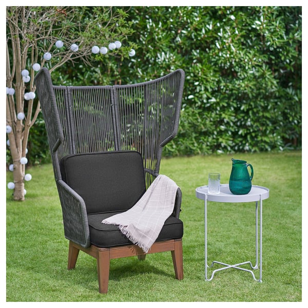 Mörk wingback stol, gröna glasvaror, gräsbevuxen bakgrund.