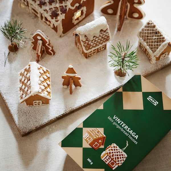 Pepparkakshus och person från IKEA VINTERSAGA, dekorerade med tallgrenar på snö, med ett paket på 300 liter.