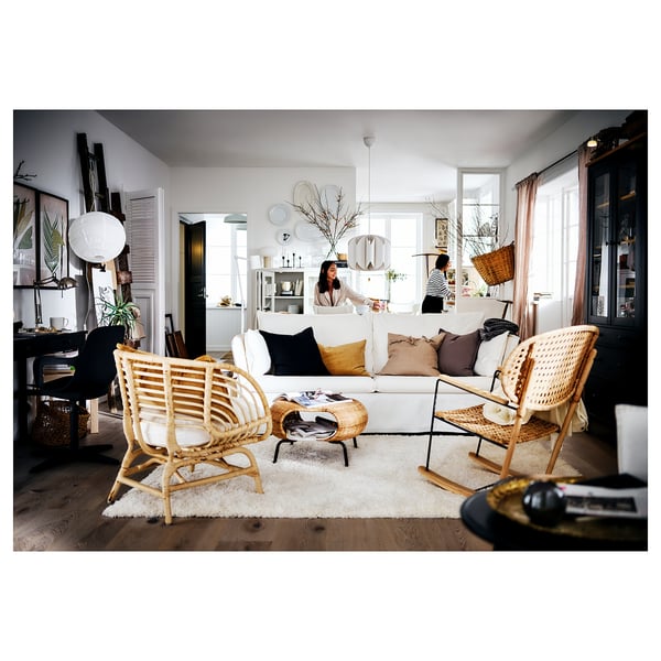 Rymligt vardagsrum med vit ryamatta, vit soffa, korgstolar och växter.