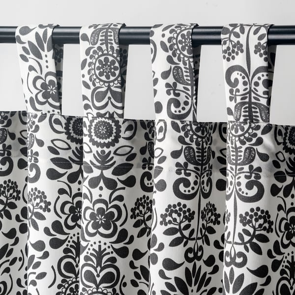 Black & white patterned curtains with floral motifs, tab headings, philtre light, provide privacy.