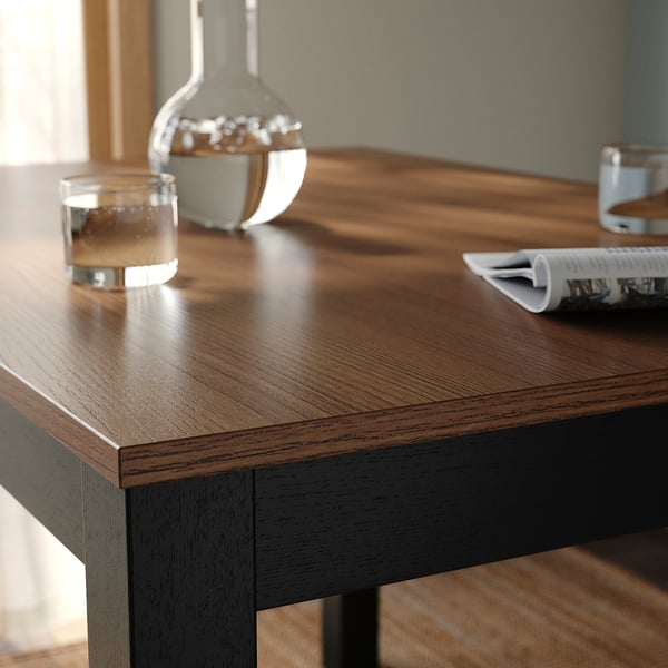 Modern wooden dining table with dark veneer and smooth edges.