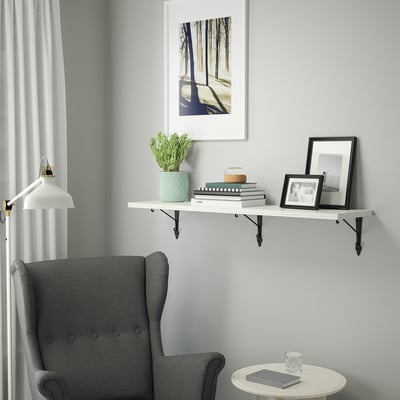 Cosy reading nook with shelf, books, plant, frame, armchair, and side table.