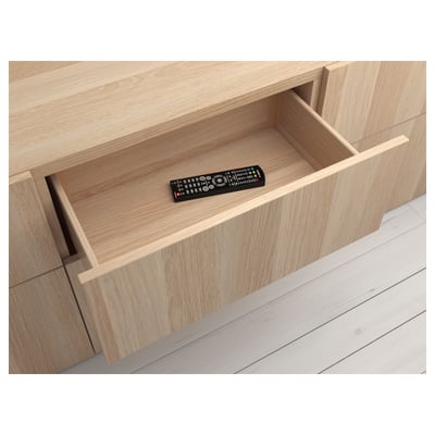 Wooden drawer with remote, part of BESTÅ storage system.