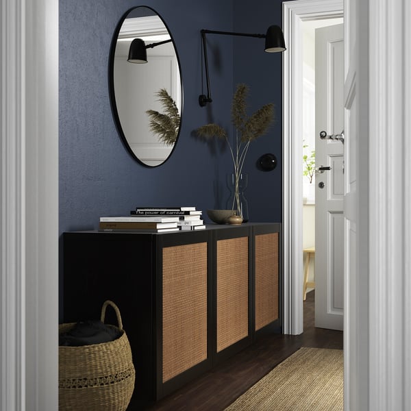 Stylish entryway with black BESTÅ sideboard, blue wall, mirror, books, plants, and light.