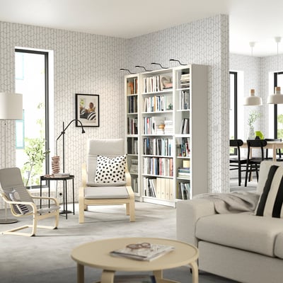 Modern living room with white BILLY bookcases, beige & black furniture, light grey wallpaper.